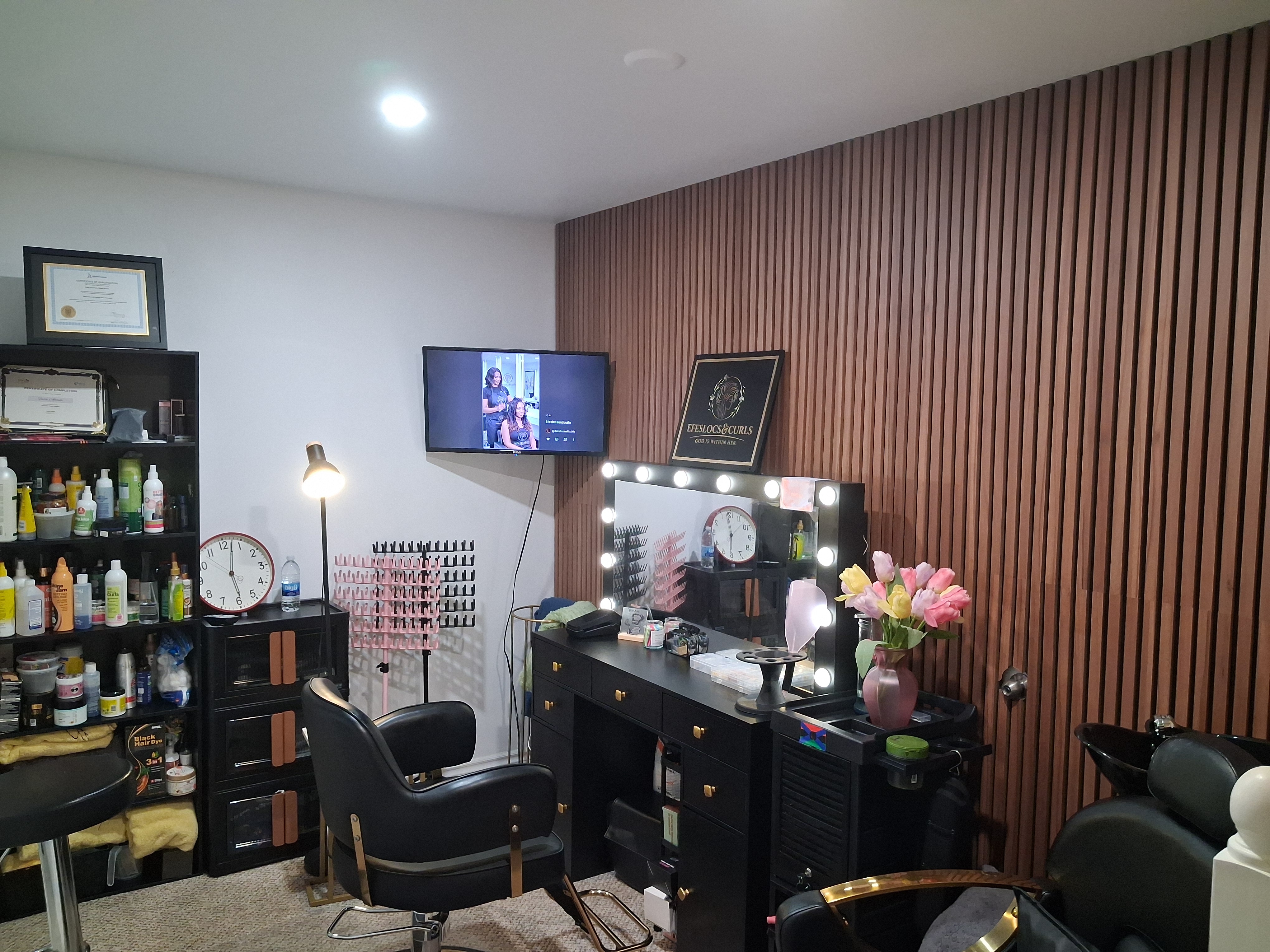 The salon's styling station with slatted wood wall and lit mirror